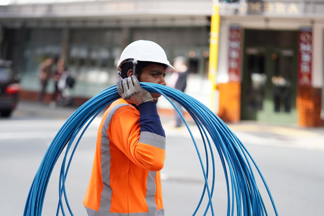 Cable installation worker wearing a hard hat, high-visibility clothing, and gloves
